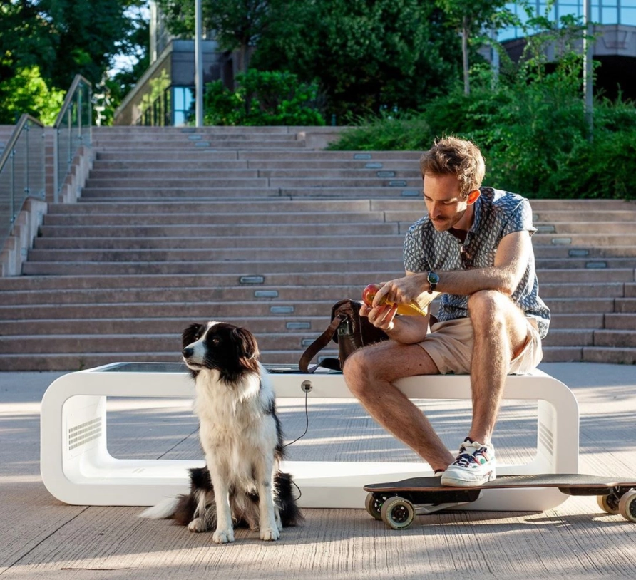 Man sitting with dog on Kuube Nano solar smart bench in public space
