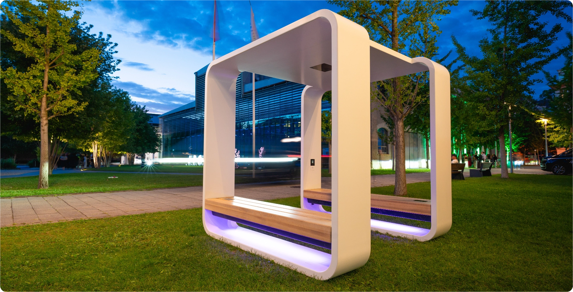 Kuube solar powered Smart Hub with integrated seating and LED lighting installed in a city park at night