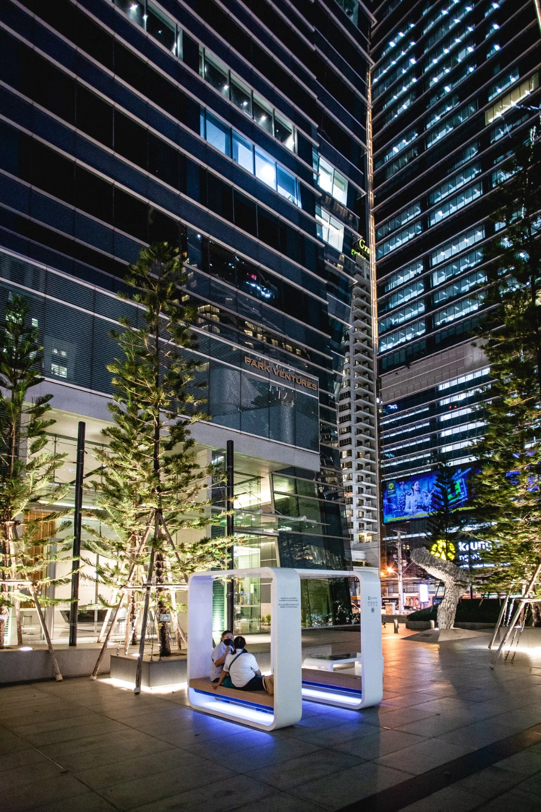 Kuube Smart Hub smart city station with blue LED lighting in a modern plaza in Bangkok at night.